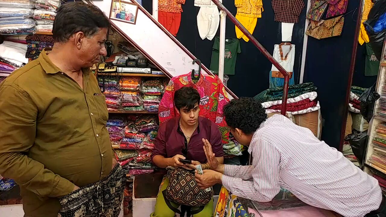 Rodrigo conversando com vendedor de uma loja, negociando o câmbio das rúpias.